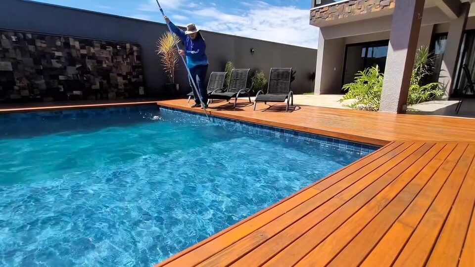 Piscina azul com deck de madeira em uma área de lazer